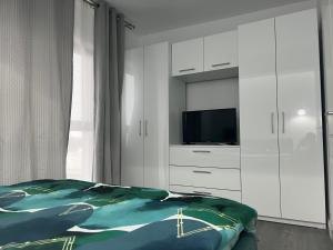een slaapkamer met een bed, een tv en witte kasten bij Apartament Otopeni lângă parc in Otopeni