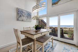 uma sala de jantar com uma mesa e cadeiras com vista para o oceano em Monterey Dune Dream em Moss Landing