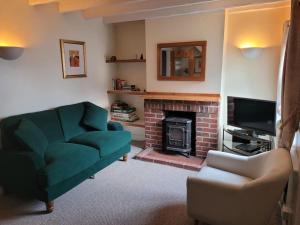 a living room with a green couch and a fireplace at Two Bedroom Cottage (rural setting with good Access links) in Grantham