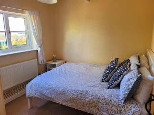 a bedroom with a bed with blue pillows and a window at Two Bedroom Cottage (rural setting with good Access links) in Grantham