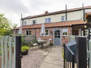 a house with a fence and a table with an umbrella at Two Bedroom Cottage (rural setting with good Access links) in Grantham