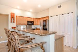 a kitchen with wooden cabinets and a island with bar stools at Ali'i Cove B1 in Kailua-Kona