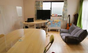 a living room with a table and a couch at ゲストハウス庵（いおり）大阪 in Fujiidera