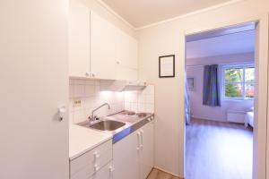 kuchnia z białymi szafkami, umywalką i oknem w obiekcie Namsskogan Familiepark & Hotell w mieście Trones
