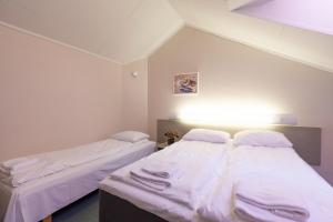 two beds in a room with white sheets at Namsskogan Familiepark & Hotell in Trones