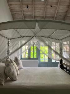 1 cama blanca con almohadas en una habitación con ventanas en Samudra Beach House, en Habaraduwa Central