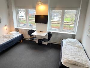 Skjernにあるrooms for rent Andersen Investのベッド2台、テーブル、椅子2脚が備わる客室です。