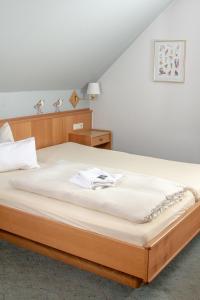 a bedroom with a large bed with white sheets at Hotel Kruse Zum Hollotal in Neuenkirchen-Vörden