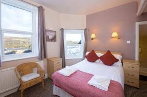 a bedroom with a bed and a chair and two windows at Dalesgate Hotel - Self Check In in Keighley