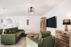 a living room with a green couch and chairs at Ferienhaus an der Wiederitz in Freital