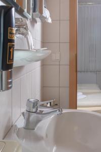 a bathroom sink with a faucet and a mirror at Hotel Kruse Zum Hollotal in Neuenkirchen-Vörden