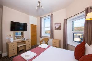 sypialnia z łóżkiem i biurkiem oraz 2 oknami w obiekcie Dalesgate Hotel - Self Check In w mieście Keighley