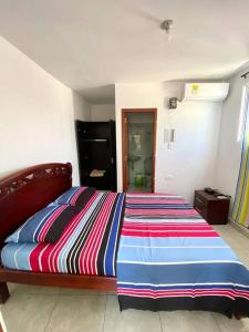 1 dormitorio con 1 cama con un colorido edredón a rayas en 2023 Apartamento Amoblado Múltiple Nogales, en Santa Marta