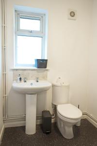 a bathroom with a toilet and a sink and a window at Guest Homes - Clacton Coastal Hideaway in Clacton-on-Sea