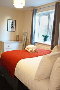 a bedroom with a bed with a red blanket and a window at Guest Homes - Clacton Coastal Hideaway in Clacton-on-Sea