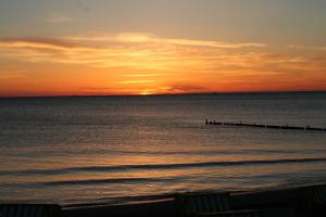 una puesta de sol sobre el océano con un muelle en Haus zum Strand 2 4, en Wustrow