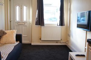 a living room with a couch and a window and a television at Guest Homes - Clacton Coastal Hideaway in Clacton-on-Sea
