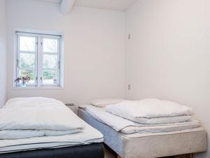 two beds in a white room with a window at Holiday home Allingåbro XXIV in Allingåbro
