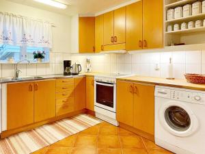 a kitchen with yellow cabinets and a washer and dryer at Holiday home SÖLVESBORG XVI in Sölvesborg