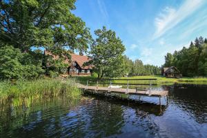 a dock in the middle of a lake with a house at Atpūtas un sporta komplekss Mednieki - atpūta dabā, pie ezera in Salainis