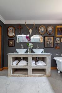 a bathroom with two sinks and pictures on the wall at Festina Lente Guesthouse in Johannesburg +84 photos