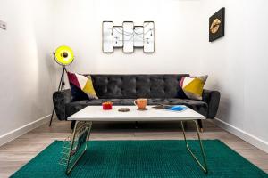 a living room with a black couch and a table at Haygarth Apartment in Knebworth