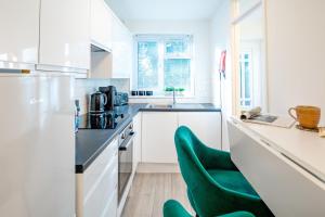 a kitchen with white cabinets and a green chair at Haygarth Apartment in Knebworth