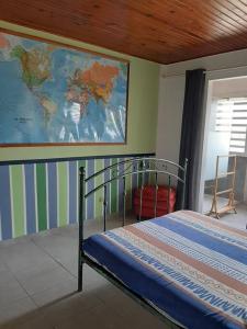 um quarto com uma cama com um mapa na parede em Maison MANZÈL à St Esprit - 20 min des plages em Grande Savane