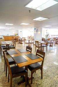 uma cafetaria com mesas e cadeiras de madeira numa sala em Marinas Maceió Hotel em Maceió