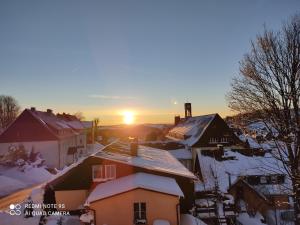 a snow covered village with the sun setting in the distance at Apartment Rumrich in Kurort Altenberg