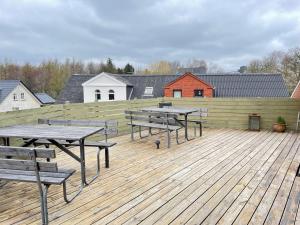 un grupo de mesas de picnic en una terraza de madera en rooms for rent Andersen Invest en Skjern