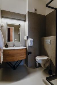 uma casa de banho com um lavatório, um WC e um espelho. em Hotel Piano em Szeged