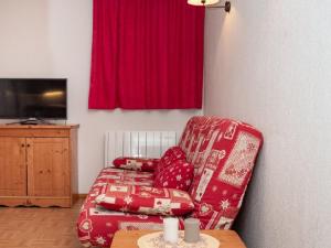 a living room with a red chair and a television at Appartement Puy-Saint-Vincent, 3 pièces, 6 personnes - FR-1-504-599 in Puy-Saint-Vincent