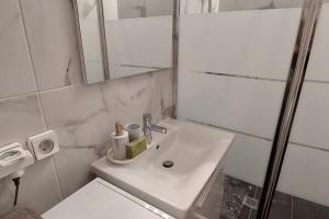 ein weißes Badezimmer mit einem Waschbecken und einem Spiegel in der Unterkunft Διαμέρισμα studioJoy4stay στο Χαλάνδρι in Athen