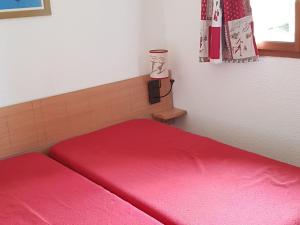 1 Schlafzimmer mit 2 roten Betten und einem Fenster in der Unterkunft Appartement Duplex 2P4 au Cœur des Chalets d'Aurouze à La Joue du Loup, Proche Commerces et Activités - FR-1-504-622 in Le Dévoluy