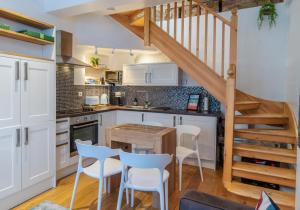 una cocina con armarios blancos y una mesa y sillas de madera. en Talbot Lane Cottage Horsham By My Getaways en Horsham