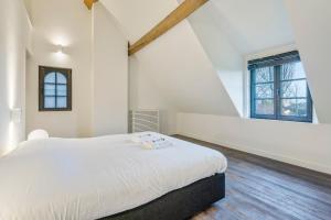 a bedroom with a white bed and a large window at d'Oude Schaapskooi, de luxe vakantiehoeve in Damme in Damme