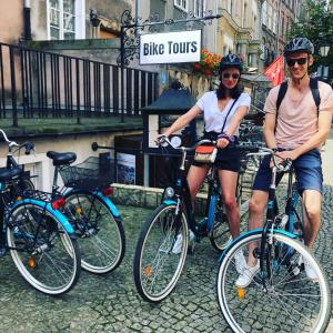 dos personas de pie con sus bicicletas en una calle en Redlowskie Klify Apartments en Gdynia