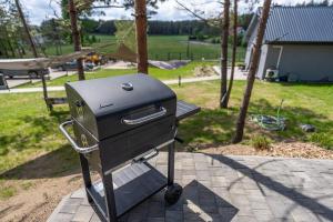 a grill on a stand on a patio at Wrzosowe Wzgórze - Domek wiejski in Kłaczno