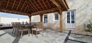 a patio with a table and chairs on a porch at Dom Peyreton Prestige cottages set in a charming wine property in Villegouge