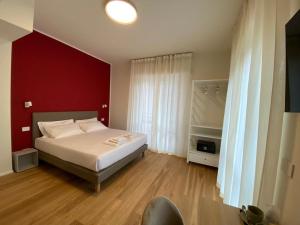a bedroom with a white bed and a red wall at FORESTERIA DANSI in Varese
