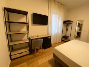 um quarto com uma cama, uma secretária e uma televisão em FORESTERIA DANSI em Varese