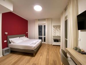 um quarto com uma cama branca e uma parede vermelha em FORESTERIA DANSI em Varese