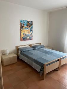 リド・ディ・イエゾロにあるAppartamento Ellidorのベッドルーム1室(ベッド1台付)が備わります。壁には絵画が飾られています。