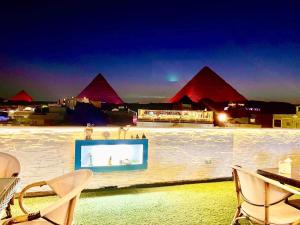 a television on a wall with pyramids in the background at Cheops Pyramids Inn in Cairo