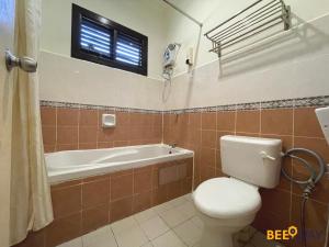 a bathroom with a toilet and a bath tub at Afamosa Villa with private pool by BeeStay in Kampong Alor Gajah