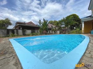 a blue swimming pool in front of a house at Afamosa Villa with private pool by BeeStay in Kampong Alor Gajah