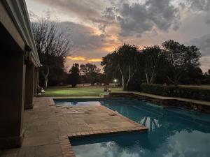 una piscina en un patio con una puesta de sol en el fondo en Country living in the City, en Midrand