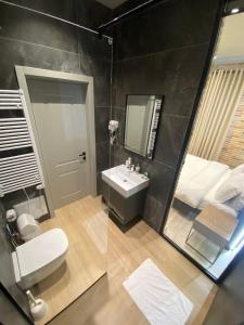 La salle de bains est pourvue de toilettes, d'un lavabo et d'un miroir. dans l'établissement Ardenica Boutique Hotel, à Lushnjë