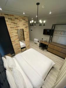 - une chambre avec un grand lit blanc et un mur en briques dans l'établissement Ardenica Boutique Hotel, à Lushnjë